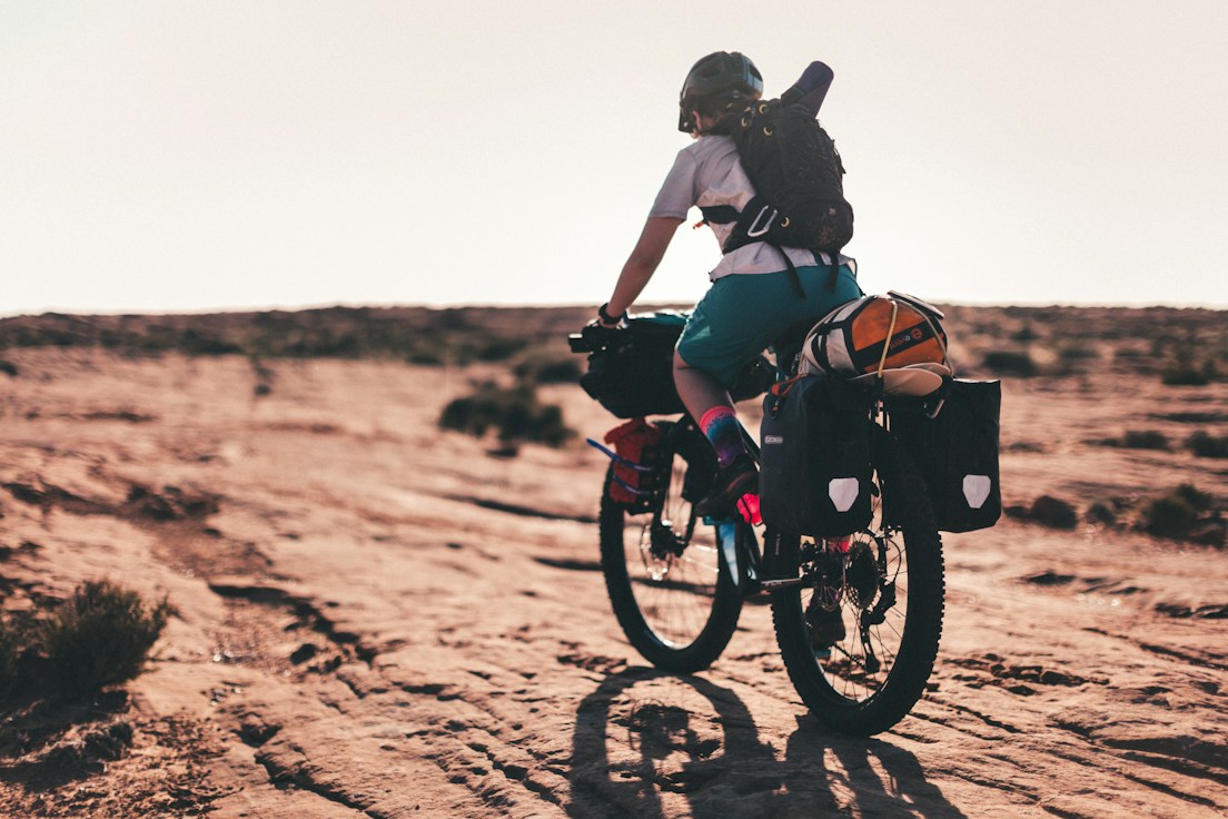 A traveller riding a loaded touring bicycle across open terrain; cycling inspiration